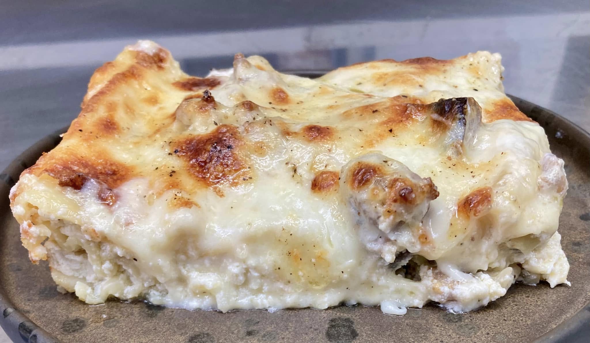 Lasagna bianca con salsiccia, funghi e provola: l’idea buona e veloce, anche con gli avanzi della domenica